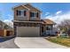 Charming two-story home with a red door, stone accents, an attached garage and well-kept landscaping at 5549 Helena St, Denver, CO 80239