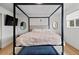 Primary bedroom with a black four-poster bed frame, featuring modern decor and natural light at 690 S Newark Ct, Aurora, CO 80012