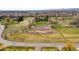 Aerial view of a grassy field with a white fence, surrounded by homes and mountains at 12940 W 75Th Ave, Arvada, CO 80005