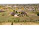 Aerial view of a large property with a house, a circular driveway, and horse facilities in a rural setting at 12940 W 75Th Ave, Arvada, CO 80005