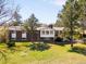Rear exterior view of a brick home with mature trees, a lawn, a patio and stairs to the upper level at 12940 W 75Th Ave, Arvada, CO 80005