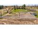 Spacious fenced horse arena with an adjacent outbuilding on a vast property with mature trees and a house in the background at 12940 W 75Th Ave, Arvada, CO 80005