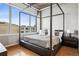 Bedroom features a modern four-poster bed, hardwood floors, and city view at 1401 Wewatta St # 911, Denver, CO 80202