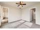A neutral primary bedroom featuring a ceiling fan, carpeted floors and adjoining bathroom and closet doors at 523 Beckwourth Ave, Fort Lupton, CO 80621