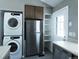 Convenient laundry area with stacked washer and dryer, stainless steel refrigerator and added shelving at 9669 W Chatfield Ave # A, Littleton, CO 80128