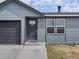 Close-up of a home's exterior showing a garage, front door, and large window with white trim at 2433 E 90Th Ave, Thornton, CO 80229