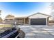 Brick ranch home with a dark gray garage door and landscaped yard at 7770 Simms St, Arvada, CO 80005