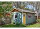 Backyard view of quaint shed with a yellow door, surrounded by mature trees and lawn at 2445 N Franklin St, Denver, CO 80205