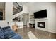 Open-concept living room with a fireplace, hardwood floors, staircase, and comfortable seating at 9225 Rockhurst St # A, Highlands Ranch, CO 80129