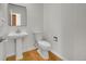 This bathroom has a clean pedestal sink, toilet, and modern fixtures against a white wall and wood floor at 17280 W 70Th Ave, Arvada, CO 80007