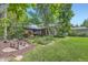 Spacious backyard with patio, lush lawn, mature trees, and decorative landscaping at 8600 W 2Nd Ave, Lakewood, CO 80226
