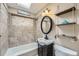 Well-lit bathroom with updated vanity, shower-tub combo, and decorative shelving at 8600 W 2Nd Ave, Lakewood, CO 80226