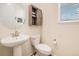 Cozy powder room featuring a pedestal sink, decorative mirror, and rustic wall cabinet at 26385 E Canal Pl, Aurora, CO 80018