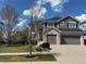 Beautiful two-story home featuring a three-car garage, manicured lawn, and a mix of stone and gray siding at 15915 E Summit Fox Ave, Parker, CO 80134
