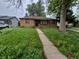 Modest single-story home with overgrown front lawn and a concrete walkway on an overcast day at 1078 Elmira St, Aurora, CO 80010