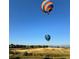 Two colorful hot air balloons float in the sky above the grassy plains and homes in the distance at 2141 Fountain Cir, Erie, CO 80516