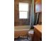 Bathroom featuring a white bathtub with stone-look tile, toilet, and window at 933 Skeel St, Brighton, CO 80601