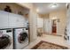Spacious laundry room features modern appliances, storage cabinets, a work area, and bathroom access at 34682 Stampede Cir, Elizabeth, CO 80107