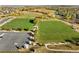 Aerial view of a sports field and parking lot surrounded by green spaces with scattered trees and blue sky backdrop at 18633 Stroh Rd # 2-104, Parker, CO 80134