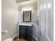 Stylish half-bathroom with a dark vanity, decorative mirror, and modern fixtures, creating a polished look at 6155 Puma Pt, Lone Tree, CO 80124