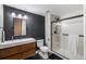 Modern bathroom featuring dark accent wall, wood vanity, and sleek glass-enclosed shower at 6155 Puma Pt, Lone Tree, CO 80124