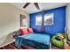 Small bedroom with blue accent wall, wood-look floors, and a brightly colored bed at 228 Birch Ave, Castle Rock, CO 80104