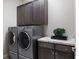 Laundry room featuring modern gray washer and dryer with counter and ample storage cabinets at 23030 E Del Norte Cir, Aurora, CO 80016