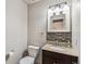 Half bathroom featuring a toilet, dark wood vanity, granite countertop, mosaic backsplash and decorative mirror at 1663 W 135Th Way, Denver, CO 80234