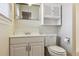 Well-lit bathroom featuring a toilet, vanity, mirror, and ample storage at 7412 W 76Th Ave, Arvada, CO 80003