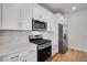 Close-up of modern kitchen with white cabinets, stainless appliances and hardwood floors at 16794 W 94Th Way, Arvada, CO 80007