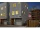 Modern townhome with gray siding, a one-car garage, and a well-maintained exterior at dusk at 3101 W 47Th Ave # 14, Denver, CO 80211