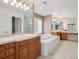 Bright bathroom featuring a soaking tub, double sink vanity and large mirrors at 902 Anaconda Ct, Castle Rock, CO 80108