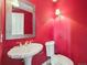 Stylish powder room featuring a pedestal sink, toilet, and vibrant red walls at 902 Anaconda Ct, Castle Rock, CO 80108