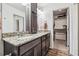 Bathroom featuring double sinks, granite counters, dark wood cabinets, and closet access at 242 S Old Hammer Ct, Aurora, CO 80018