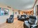 Well-lit living room with hardwood floors, three reclining chairs, and an open layout to the kitchen at 3691 Bucknell Dr, Highlands Ranch, CO 80129