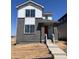 Two-story home showcasing a gray brick facade, white accents, large windows, and a vibrant red front door at 5456 N Elk St, Aurora, CO 80019