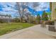 Fenced backyard with a concrete patio, table with chairs, and mature trees at 4640 Fairplay Way, Denver, CO 80239