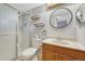 Bright bathroom featuring a glass shower, floating shelves, round mirror, and wooden vanity cabinet at 18056 E Mansfield Ave, Aurora, CO 80013