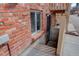 Exterior brick building with window and metal grate door entrance to basement area at 1585 S Holly St # 109, Denver, CO 80222
