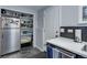 Close up of kitchen featuring white counters, stainless steel appliances, and pantry at 1585 S Holly St # 109, Denver, CO 80222