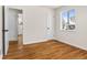 Bright bedroom featuring hardwood floors, white walls, and natural light from a window at 7555 E 22Nd Ave, Denver, CO 80207
