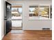 Bright entryway with hardwood floors, a black front door, and a large window view of the snow covered front yard at 7555 E 22Nd Ave, Denver, CO 80207