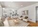 Open living room with hardwood floors, white furniture, and a view into the bright white kitchen at 7555 E 22Nd Ave, Denver, CO 80207