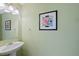 A half bathroom features a pedestal sink, decorative mirror, and colorful artwork at 16256 E Otero Pl, Englewood, CO 80112