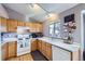 Bright kitchen with wood cabinets, white appliances, and a window overlooking the backyard at 2482 Purcell Pl, Brighton, CO 80601