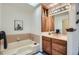 Bathroom features a bathtub with tile surround and vanity with wood cabinets for a relaxing bathing experience at 6487 W Weaver Ave, Littleton, CO 80123