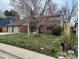 Cozy two-story home with a brick front, two-car garage, and a partially shaded front lawn at 6487 W Weaver Ave, Littleton, CO 80123