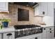 Modern kitchen features stainless steel range, brick backsplash, and white cabinetry at 2948 S Clarkson St, Englewood, CO 80113
