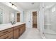 Well-lit bathroom showcasing marble floors, glass enclosed shower, and wood cabinetry at 8686 Pennycress Dr, Littleton, CO 80125