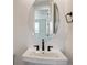 Modern bathroom features a pedestal sink with oval mirror and black hardware at 8686 Pennycress Dr, Littleton, CO 80125